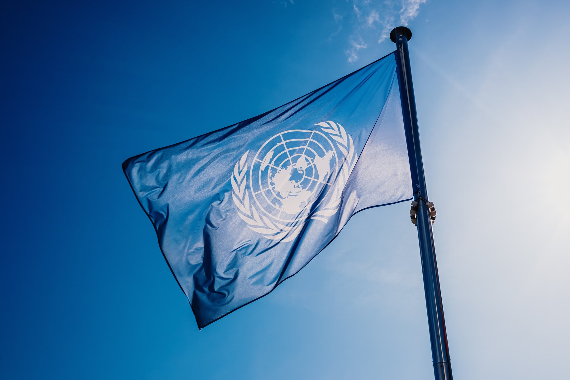 UN Flag Waved against the Sun and Blue Sky.